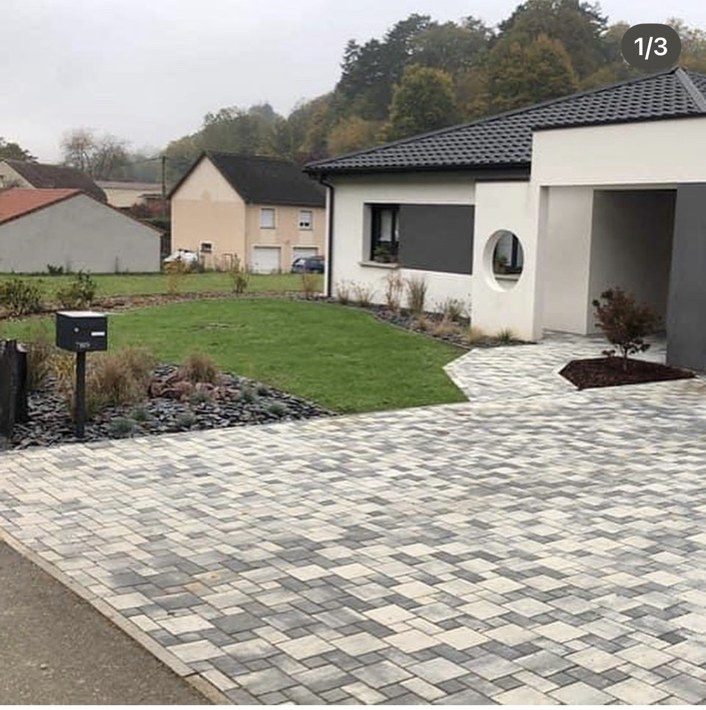 Allée d'entrée pavée, gazon et massif minéral devant une maison neuve